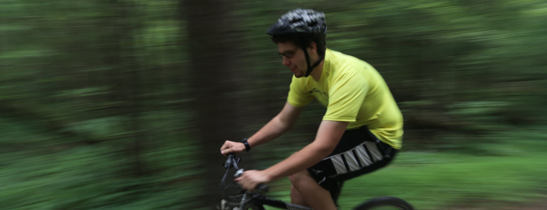 A Scout mountain bikes down a side road at camp